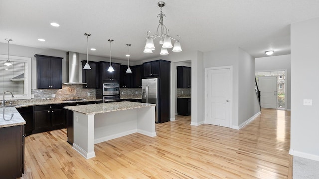 15365 Eagle Creek Way, Apple Valley, MN 55124 - kitchen featuring wall chimney range hood, appliances with stainless steel finishes, a kitchen island, backsplash, and light wood-type flooring