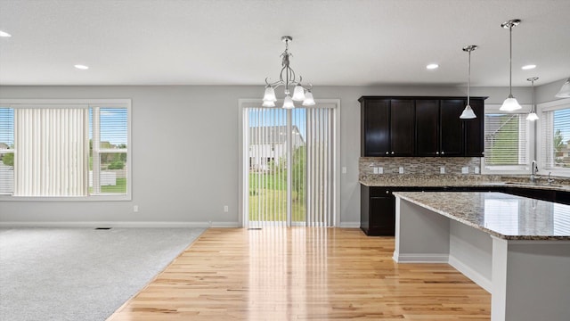 15365 Eagle Creek Way, Apple Valley, MN 55124 - kitchen with a sink, light wood-style floors, a chandelier, baseboards, and light stone counters