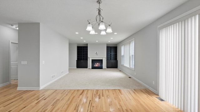 15365 Eagle Creek Way, Apple Valley, MN 55124 - unfurnished living room with wood finished floors, a chandelier, baseboards, a glass covered fireplace, and recessed lighting