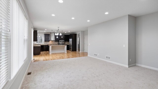 15365 Eagle Creek Way, Apple Valley, MN 55124 - unfurnished living room with light carpet, a chandelier, recessed lighting, baseboards, and a sink
