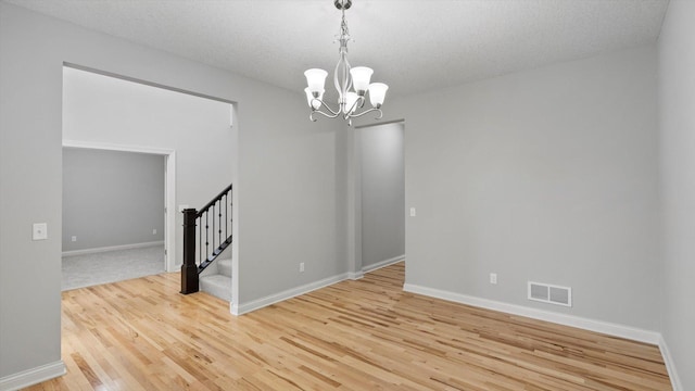15365 Eagle Creek Way, Apple Valley, MN 55124 - unfurnished room with stairs, a chandelier, light wood-type flooring, baseboards, and a textured ceiling