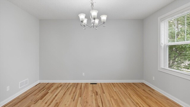 15365 Eagle Creek Way, Apple Valley, MN 55124 - spare room featuring a chandelier, light wood-style floors, and baseboards