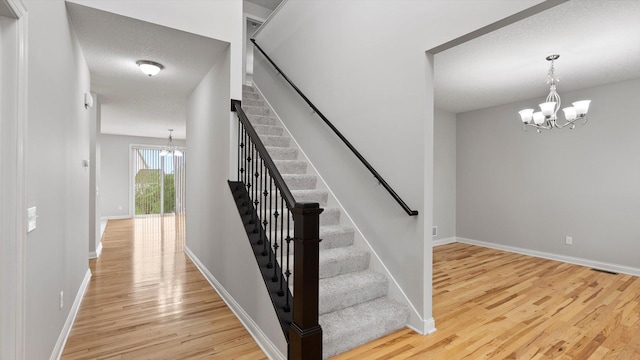 15365 Eagle Creek Way, Apple Valley, MN 55124 - staircase with a chandelier, wood finished floors, baseboards, and a textured ceiling