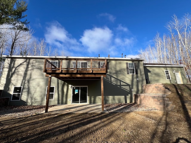 rear view of house with a wooden deck and a patio area