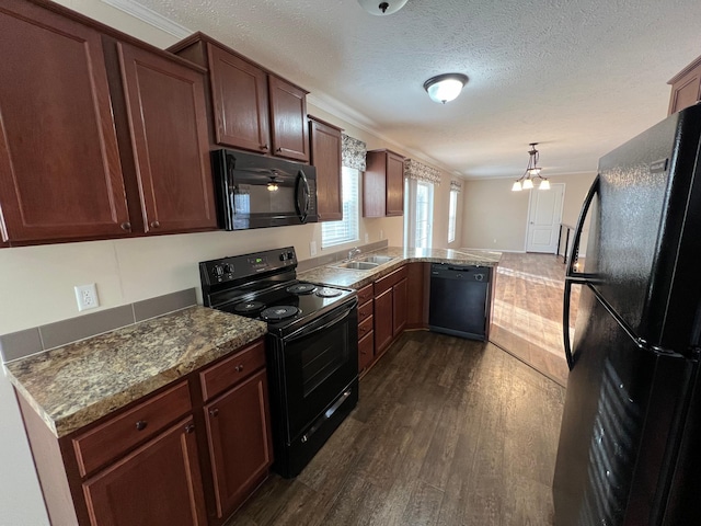 kitchen featuring black appliances, a sink, dark wood-style flooring, a peninsula, and ornamental molding