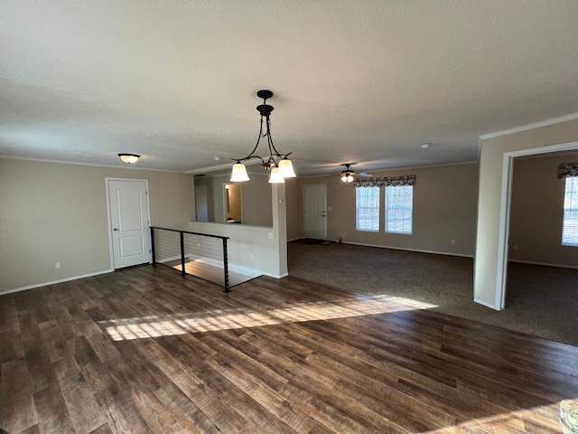 unfurnished living room featuring crown molding, baseboards, dark wood-type flooring, ceiling fan, and a textured ceiling