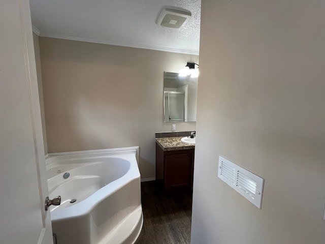 full bath with a bath, wood finished floors, vanity, ornamental molding, and a textured ceiling