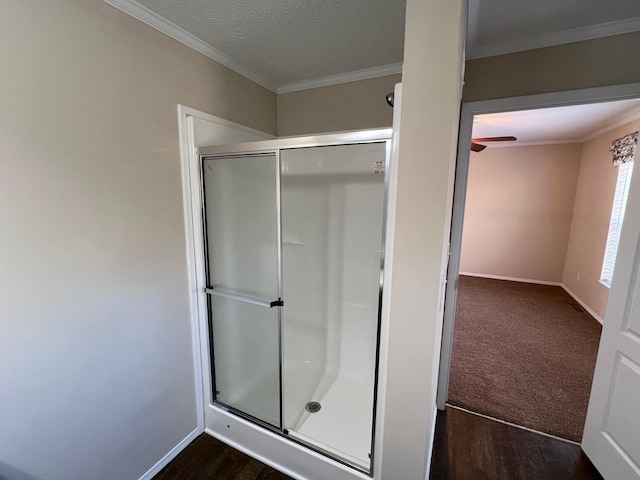 full bath with a stall shower, ornamental molding, a ceiling fan, baseboards, and wood finished floors