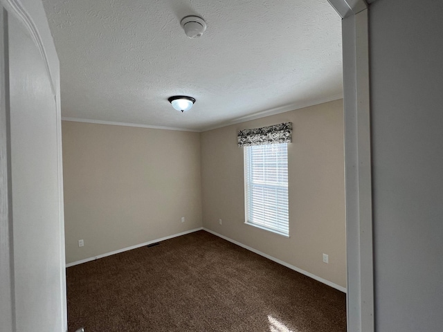 empty room featuring ornamental molding, dark carpet, baseboards, and a textured ceiling