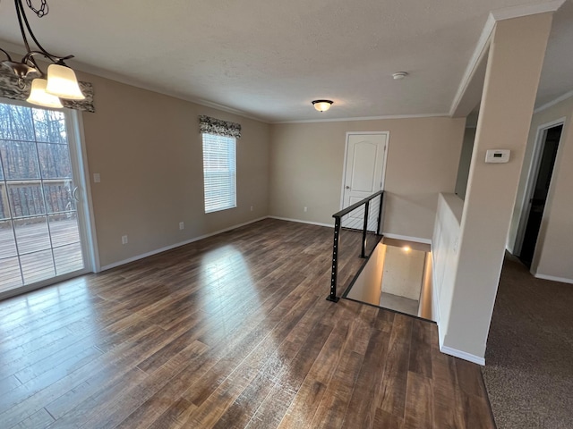 unfurnished room with plenty of natural light, crown molding, dark wood-style floors, a chandelier, and baseboards