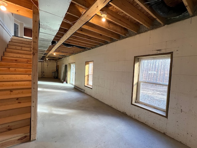 basement with stairway and a baseboard heating unit