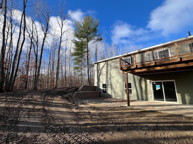 rear view of house featuring a deck, a patio, and a carport