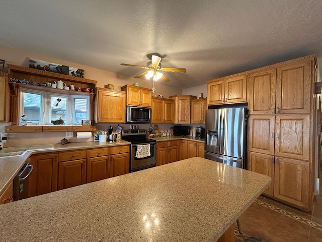 14620 Thomas Rd, Lake Park, MN 56554 - kitchen featuring stainless steel appliances, ceiling fan, brown cabinets, and a textured ceiling