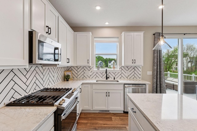 1049 Fabel Ln, Waconia, MN 55387 - kitchen with stainless steel appliances, a sink, white cabinetry, wood finished floors, and decorative light fixtures