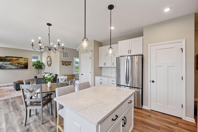 1049 Fabel Ln, Waconia, MN 55387 - kitchen featuring freestanding refrigerator, a kitchen island, light wood finished floors, white cabinetry, and hanging light fixtures