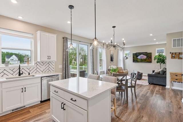 1049 Fabel Ln, Waconia, MN 55387 - kitchen with stainless steel dishwasher, a sink, open floor plan, light wood-style flooring, and decorative backsplash