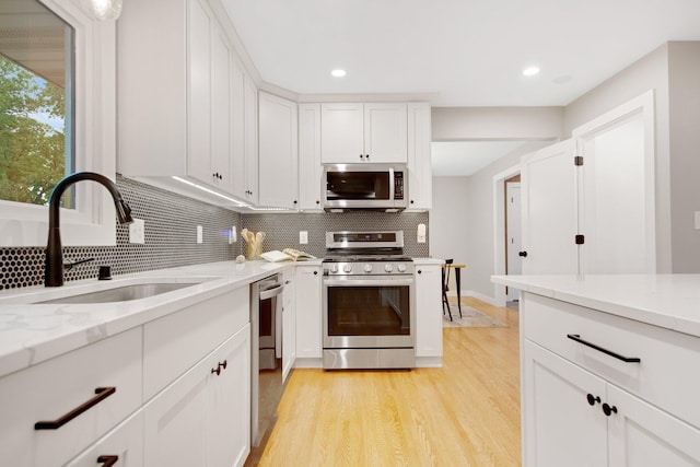 2400 Oakwood Dr, Burnsville, MN 55306 - kitchen with appliances with stainless steel finishes, a sink, backsplash, light stone countertops, and white cabinets