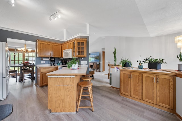 3062 196th Ave NE, East Bethel, MN 55011 - kitchen featuring a chandelier, white appliances, light countertops, brown cabinetry, and lofted ceiling