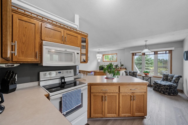 3062 196th Ave NE, East Bethel, MN 55011 - kitchen featuring white appliances, a peninsula, light countertops, brown cabinetry, and a textured ceiling