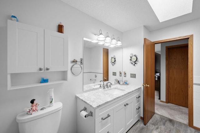 3062 196th Ave NE, East Bethel, MN 55011 - bathroom featuring vanity, toilet, wood finished floors, a textured ceiling, and a skylight