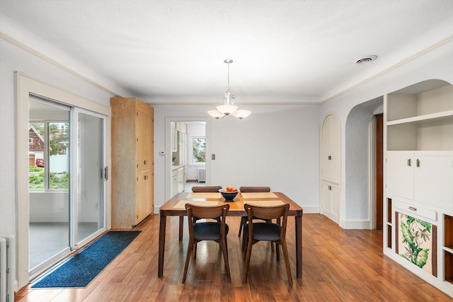 2708 Chowen Ave S, Minneapolis, MN 55416 - dining area with light wood-style flooring, arched walkways, radiator, and a chandelier
