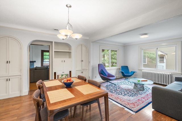 2708 Chowen Ave S, Minneapolis, MN 55416 - dining space featuring radiator heating unit, arched walkways, light wood-type flooring, crown molding, and a chandelier