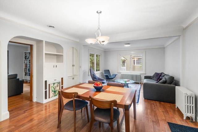2708 Chowen Ave S, Minneapolis, MN 55416 - dining room with radiator heating unit, arched walkways, light wood-style floors, a chandelier, and crown molding