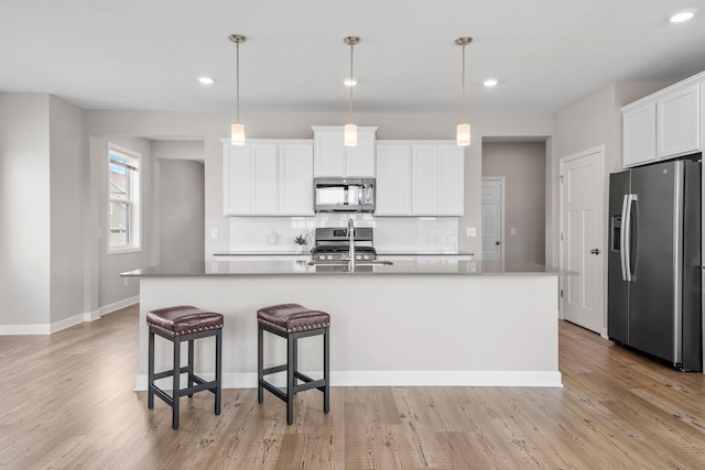 14520 109th Ave N, Maple Grove, MN 55369 - kitchen featuring stainless steel appliances, tasteful backsplash, light wood-style floors, white cabinets, and a kitchen island with sink