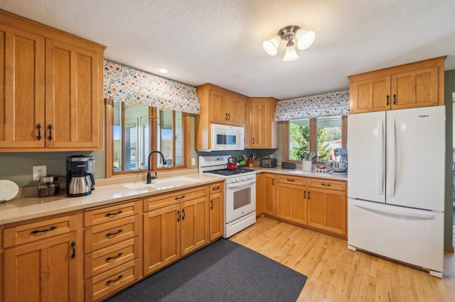 2929 170th St, Frederic, WI 54837 - kitchen featuring white appliances, a sink, light countertops, light wood finished floors, and a textured ceiling