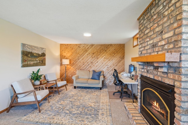 2929 170th St, Frederic, WI 54837 - carpeted living area with a fireplace, an accent wall, baseboards, wooden walls, and a textured ceiling