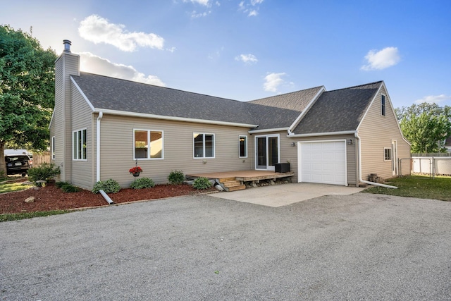 view of front facade with an attached garage, asphalt driveway, a shingled roof, and a chimney