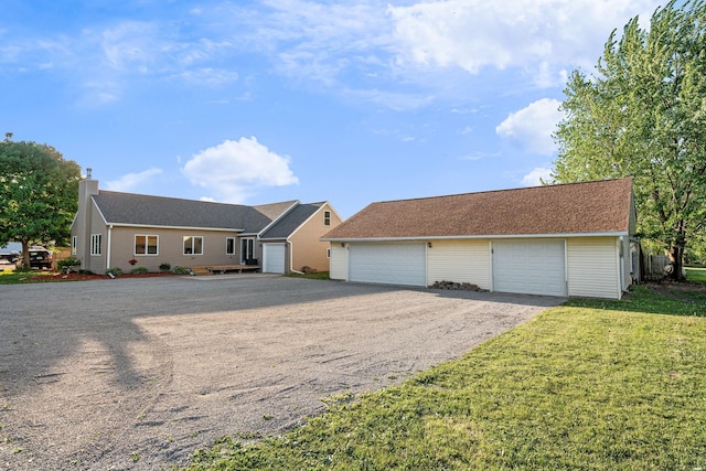 ranch-style house with a chimney, a detached garage, a front lawn, and an outbuilding