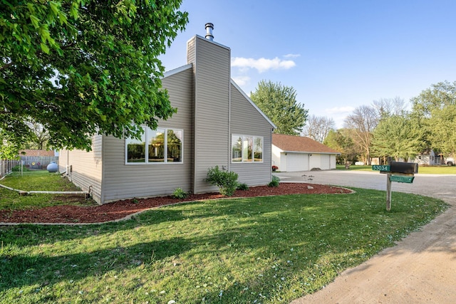 view of home's exterior with a detached garage, a chimney, and a yard