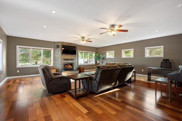 living area featuring baseboards, hardwood / wood-style flooring, a stone fireplace, plenty of natural light, and recessed lighting