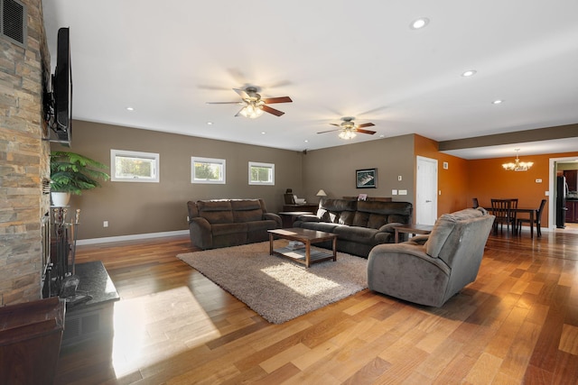 living area with light wood finished floors, a chandelier, a ceiling fan, baseboards, and recessed lighting