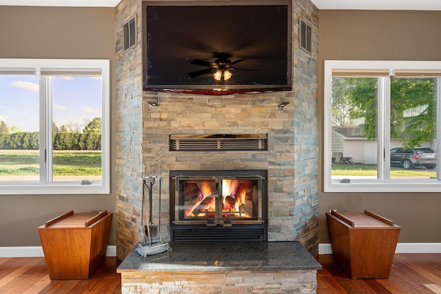 detailed view of baseboards, wood finished floors, a fireplace, and a ceiling fan