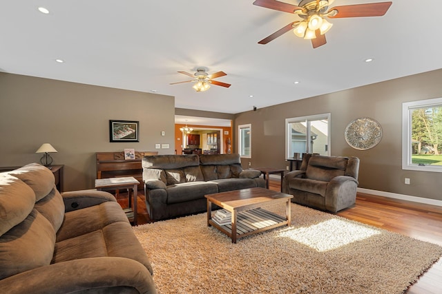 living area with light wood finished floors, ceiling fan, baseboards, recessed lighting, and a chandelier