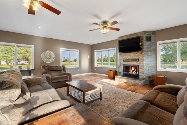 living area featuring ceiling fan, wood finished floors, baseboards, and plenty of natural light