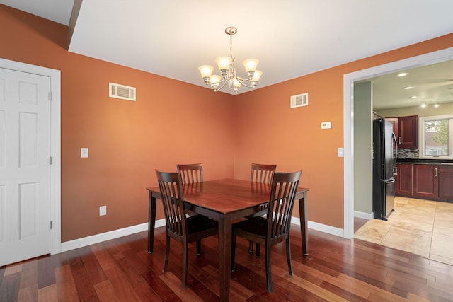 dining area featuring a chandelier, light wood-style flooring, and baseboards