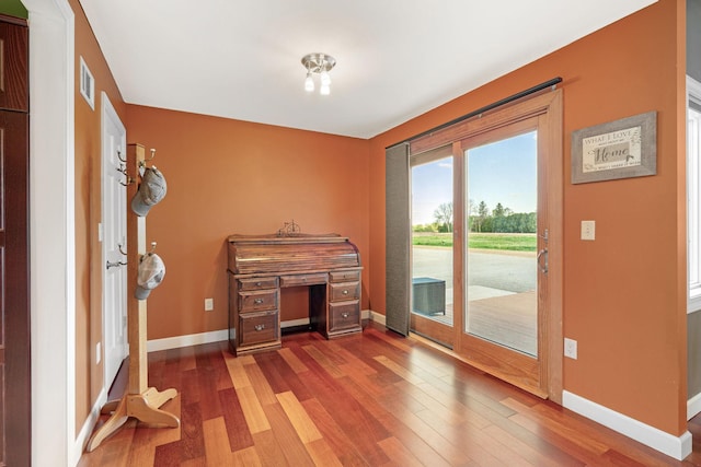 unfurnished office with baseboards and wood finished floors