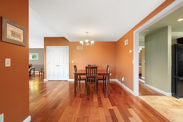 dining space with light wood finished floors, a chandelier, and baseboards