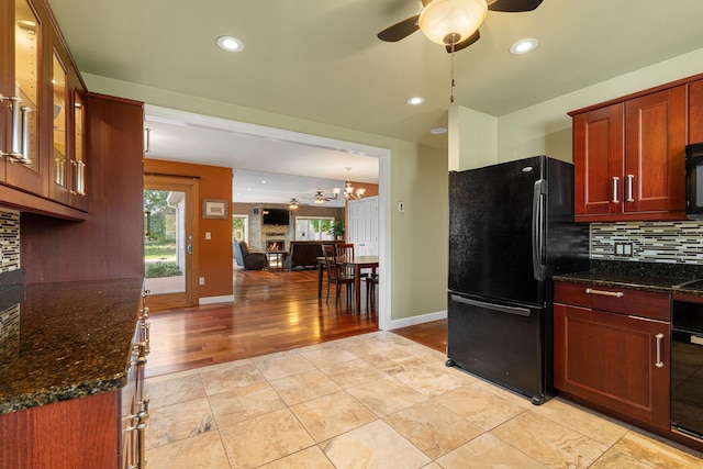 kitchen featuring black appliances, ceiling fan, decorative backsplash, dark stone countertops, and glass insert cabinets
