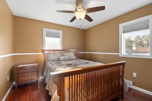 bedroom with a wainscoted wall, wood finished floors, baseboards, and a ceiling fan