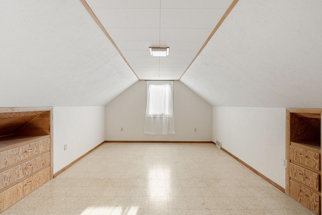 additional living space featuring baseboards, light floors, and lofted ceiling