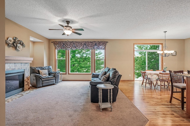 10025 Toledo Dr N, Brooklyn Park, MN 55443 - living area with healthy amount of natural light, a ceiling fan, a chandelier, a textured ceiling, and a tiled fireplace