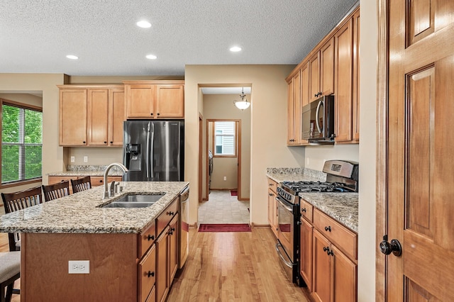 10025 Toledo Dr N, Brooklyn Park, MN 55443 - kitchen featuring appliances with stainless steel finishes, a sink, a kitchen breakfast bar, healthy amount of natural light, and a textured ceiling