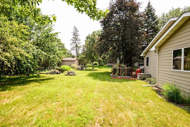 3760 Trenton Ln N, Plymouth, MN 55441 - view of grassy yard with an outdoor fire pit and an outbuilding