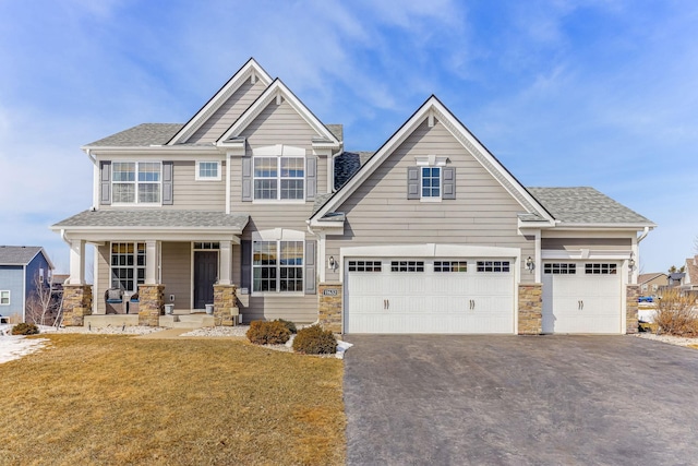 11632 Riverstone Trl, Woodbury, MN 55129 - craftsman-style house with asphalt driveway, covered porch, a front lawn, stone siding, and roof with shingles