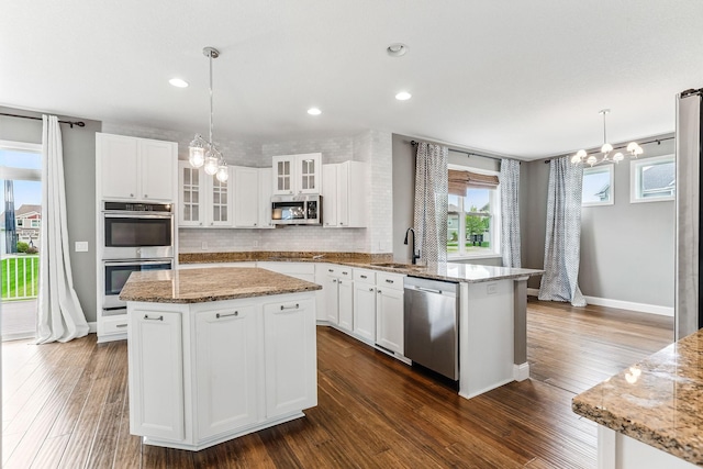 11632 Riverstone Trl, Woodbury, MN 55129 - kitchen featuring stainless steel appliances, a chandelier, a peninsula, backsplash, and a sink