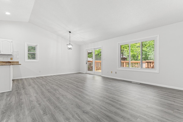 500 Ridge Ln, Chaska, MN 55318 - unfurnished living room with vaulted ceiling, a chandelier, light wood-type flooring, baseboards, and a textured ceiling